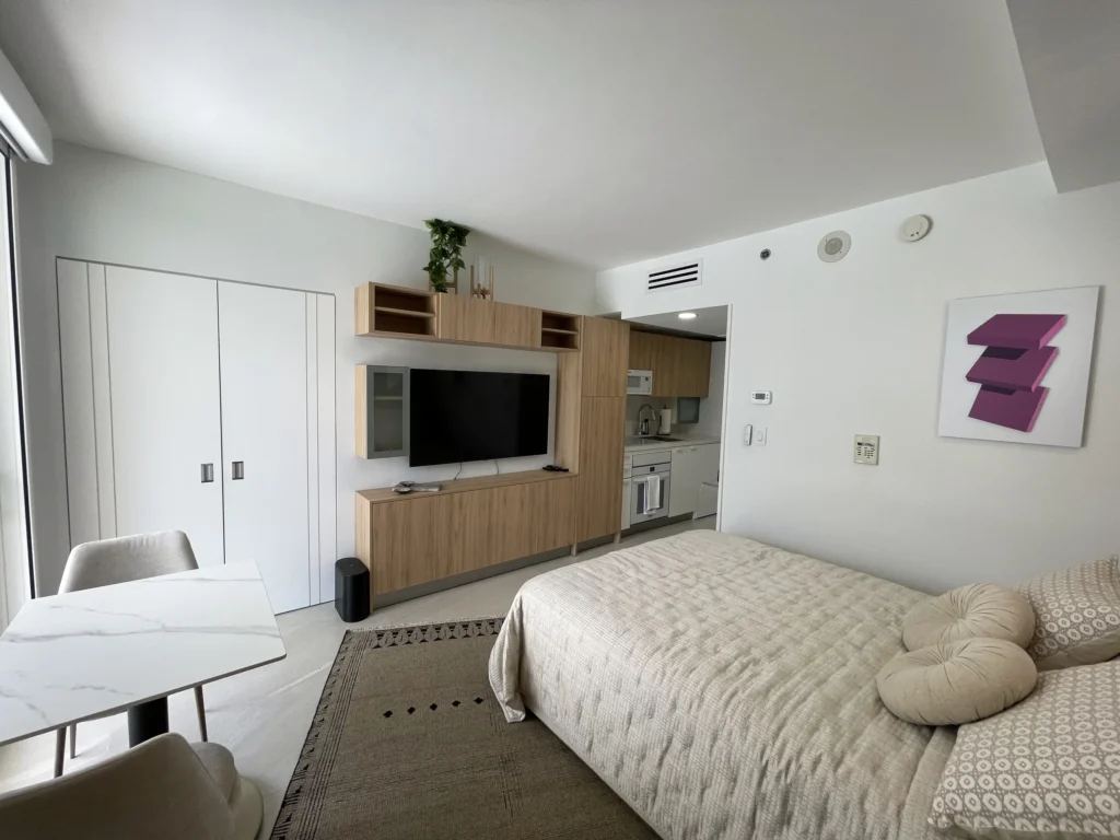 Estudio con mueble de TV a medida y cocina al fondo / Studio with custom TV unit and kitchen beyond · Unidad 312, 7000 Island Blvd, Aventura FL