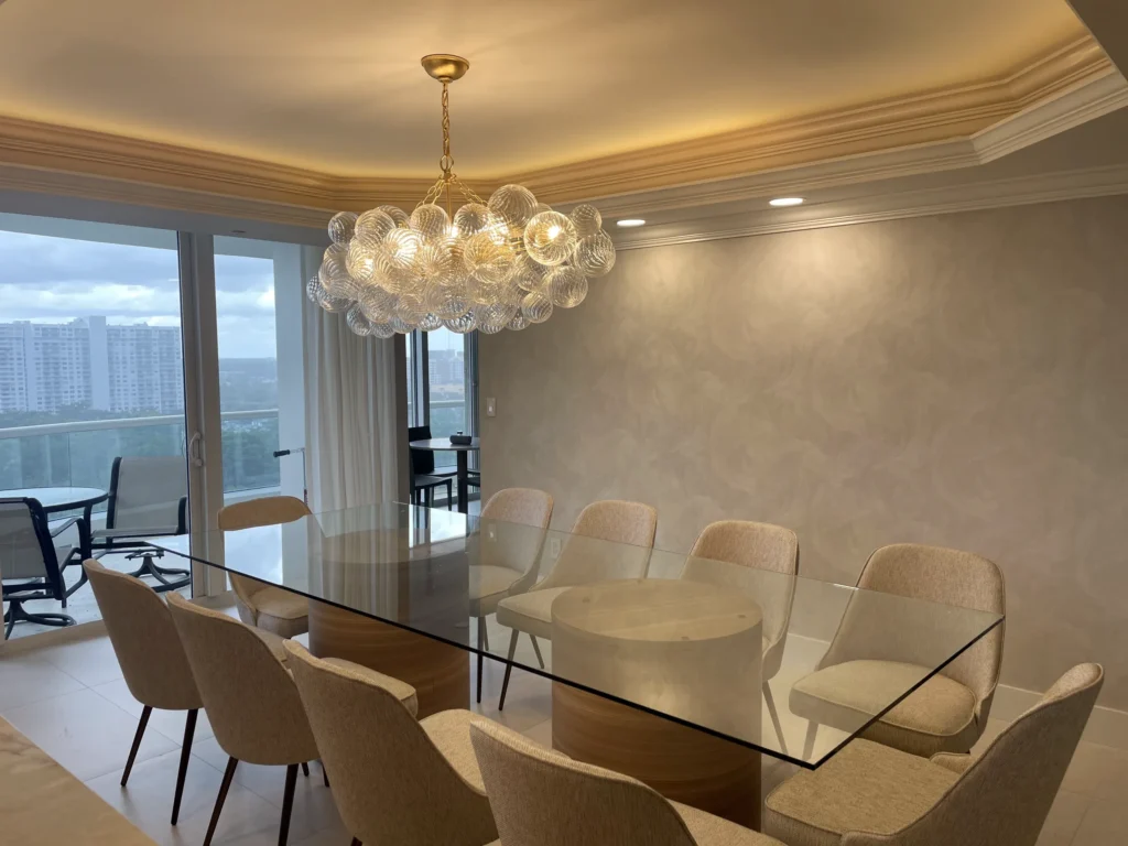 Comedor con lámpara de burbujas de vidrio e iluminación de cornisa / Dining room with glass bubble chandelier and cove lighting · Sol y Luna Works, Aventura FL